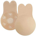 Shapelux Lifting Pads for Invisible Breast Lift är beige, återanvändbara silikonöverdrag med kaninöronform och stark tejp. Det ena visar den släta framsidan, det andra visar hjärtformade utskärningar och texturerad tejp för ett alternativ till en strapless-bh.
