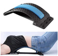 Fashiongirl Pro Back Stretcher, som visas ensam med en blå dyna, demonstreras också av en person som bär en svart skjorta och blå jeans och använder den för ländryggsstöd och hållningskorrigering.