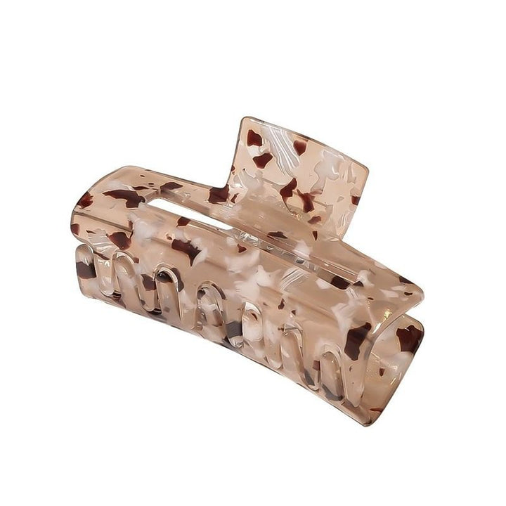 SOHO Aria Hair Claw - Light Tortoise har en beige och brun sköldpaddsmönstrad acetatdesign med böjda kanter och sammanlänkade tänder, tillverkad av SOHO för att säkert hålla tjockt hår på plats.