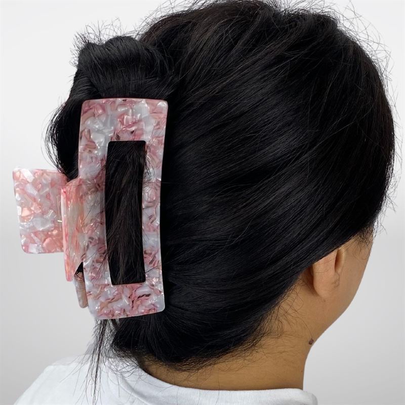 A person with dark hair in a low twist, secured by the SOHO Clara Hair Claw - Light Coral. The XL hair clip holds thick hair securely. They wear a white shirt and are shown from the back against a plain background.