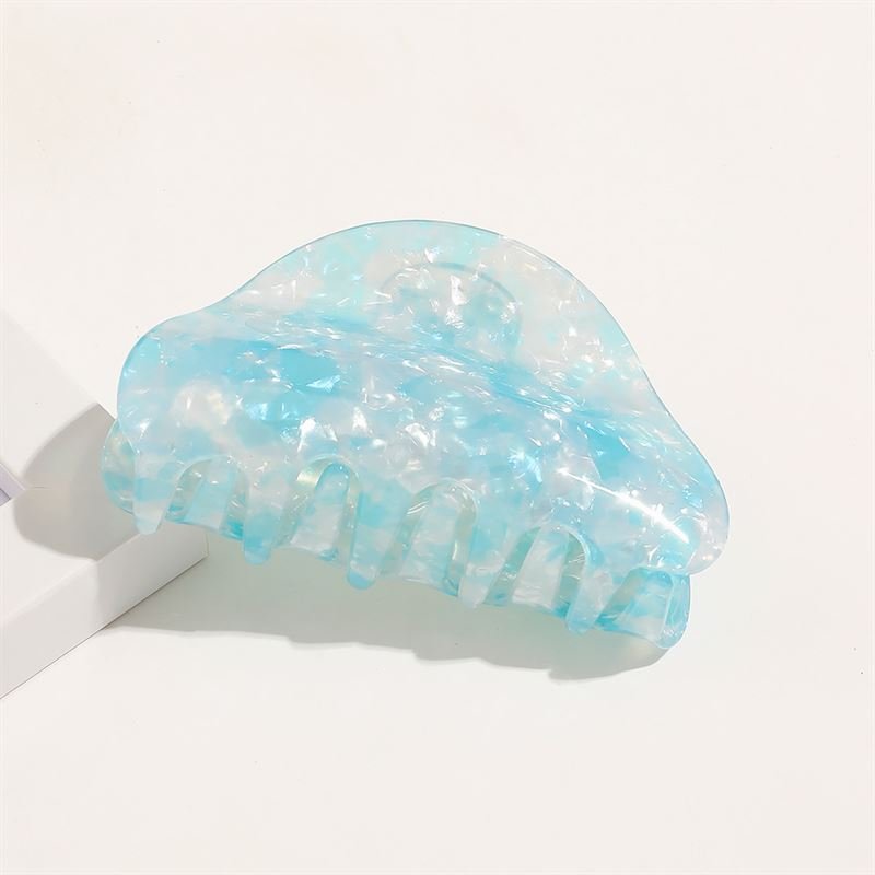 The SOHO Cleo Hair Claw in Crystal Blue features a large, translucent blue and white marble pattern with wide teeth, displayed on a white surface.