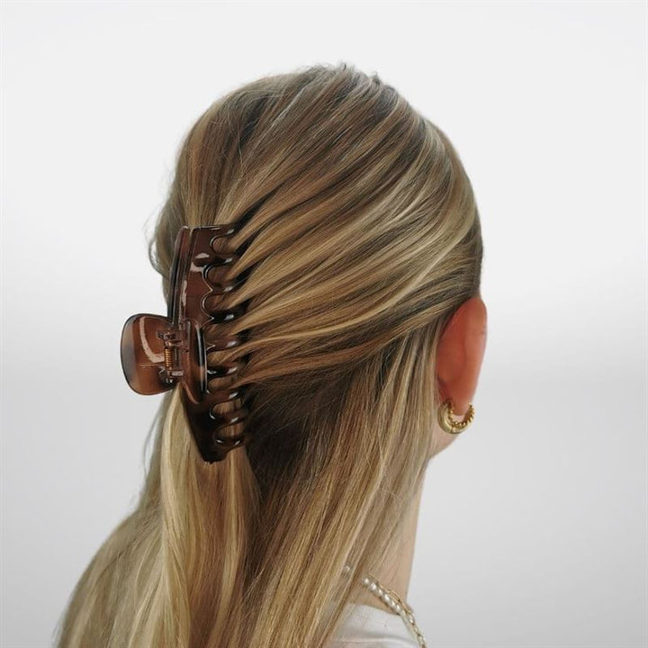 A woman with blonde hair in a half-up, half-down style secured by the SOHO Kana Hair Claw - Tortoise, known for its strong grip. She wears gold hoop earrings and a necklace, shown from the back—suitable for all hair types.