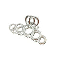 Sju glänsande metallringar i olika storlekar, inspirerade av de eleganta kurvorna på SOHO Metal Hair Claw - Silver från SOHO, är ordnade i en rad som en larv på en vit bakgrund.