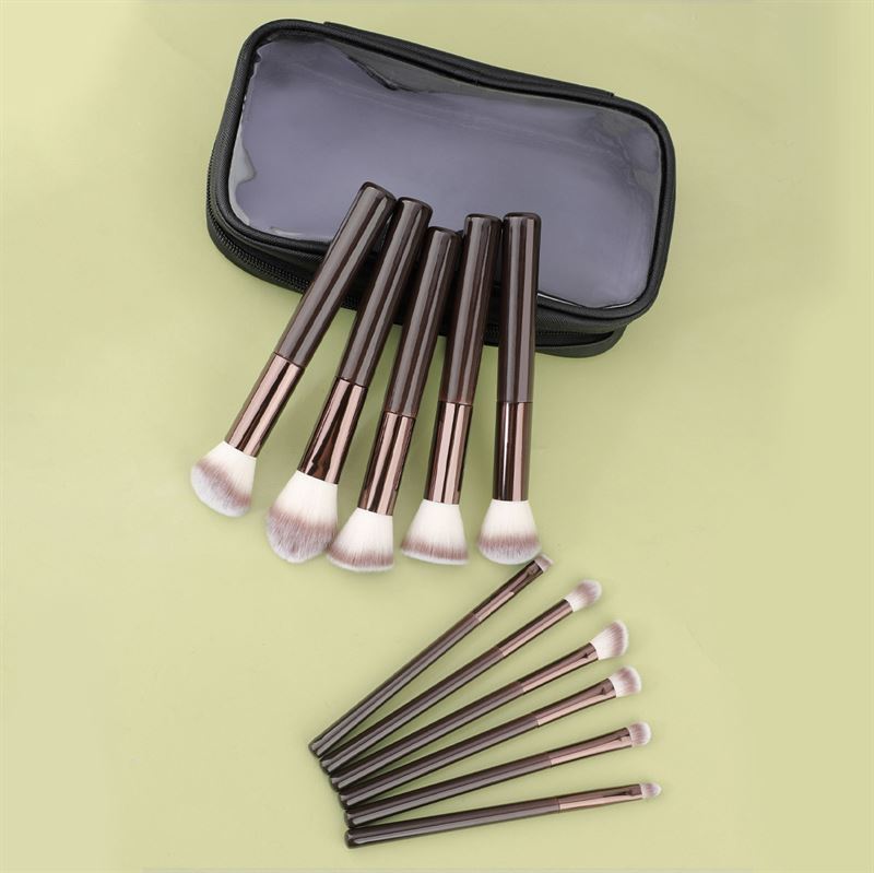 The Technique PRO Chocolate Bronze Makeup Brush Set includes 11 brushes with dark handles and light bristles, displayed in two rows next to a transparent makeup bag on a light green background.
