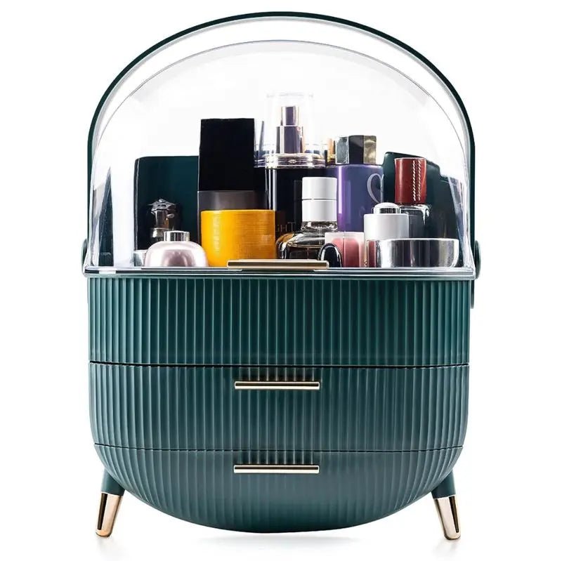 The UNIQ Retro Makeup Box Organiser in Dark Mint/Dark Green features two ribbed drawers, gold handles and legs, and a clear dome cover for neatly storing your skincare and makeup essentials.