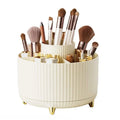 UNIQ Rotating Makeup Organiser i krämvit har en ribbad design i flera nivåer med fack och guldben, vilket gör det enkelt att förvara och organisera borstar, läppstift, pennor och skönhetsprodukter.